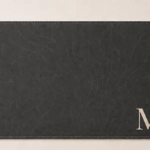 Charcoal desk mat with a large ivory monogram initial and a printed name
